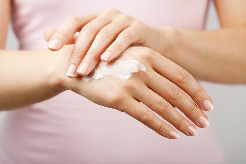 A woman applying hand lotion.