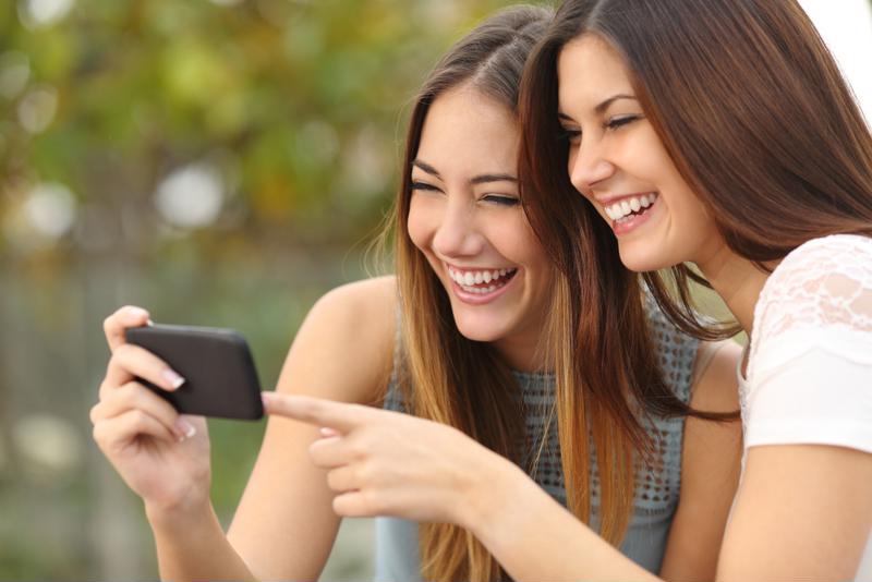 Two young women happily using a mobile application.