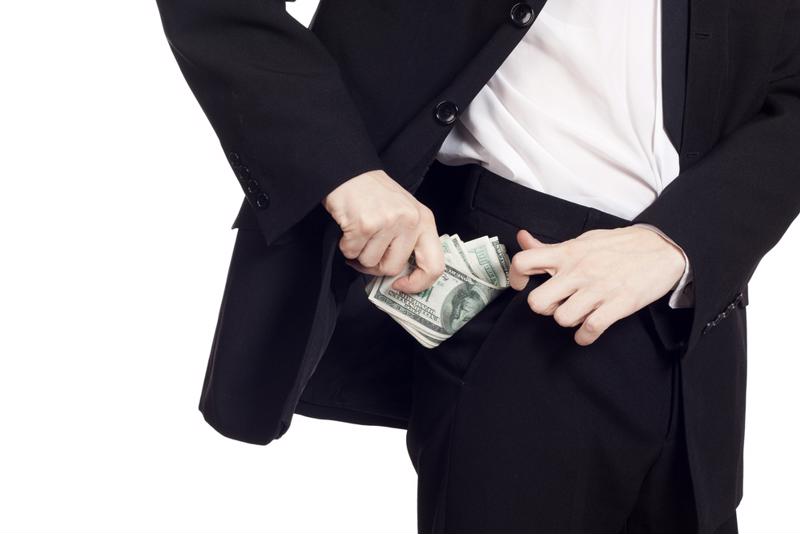 A businessman stuffs money in his pocket.